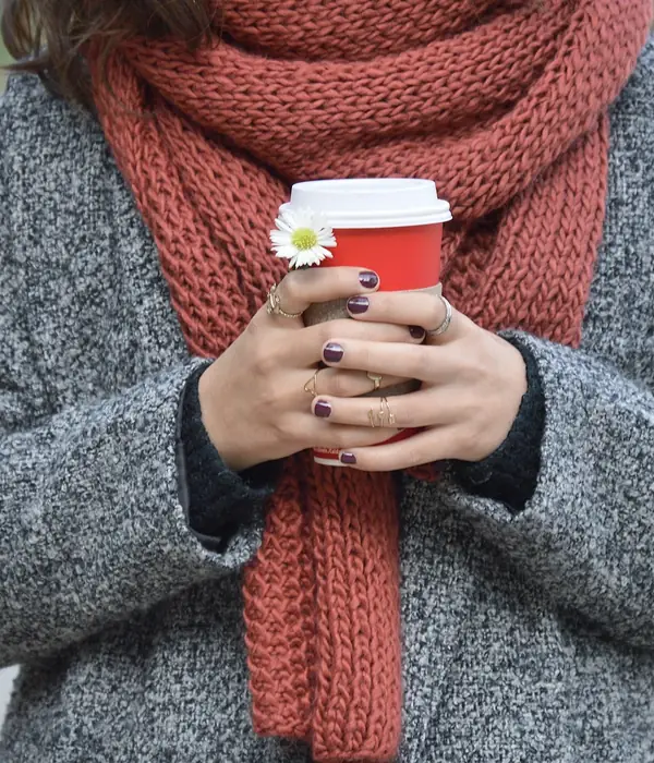 Vrouw met rode wollen sjaal en warme koffie